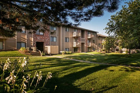 an apartment building with a green lawn and trees