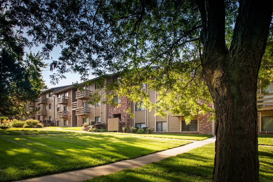 a row of apartment buildings with green grass and trees