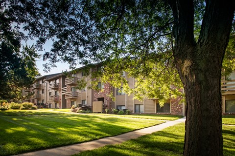 a row of apartment buildings with green grass and trees