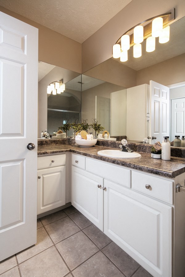 a bathroom with white cabinets and a sink and a mirror