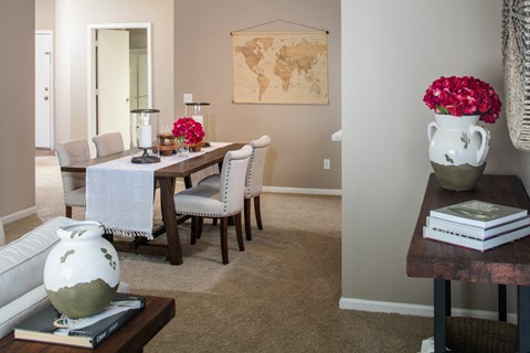 a dining room with a table and chairs and a vase with flowers