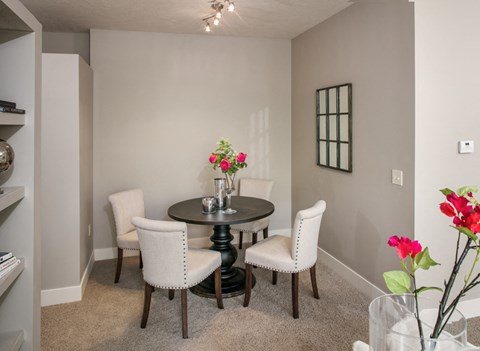 A dining room with a round table and four chairs.