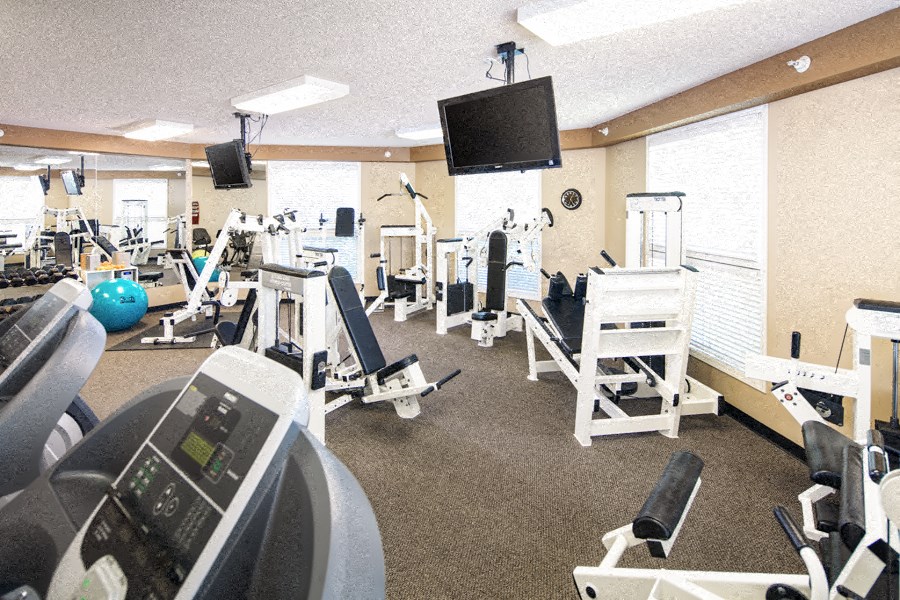 a gym with various exercise equipment and a tv
