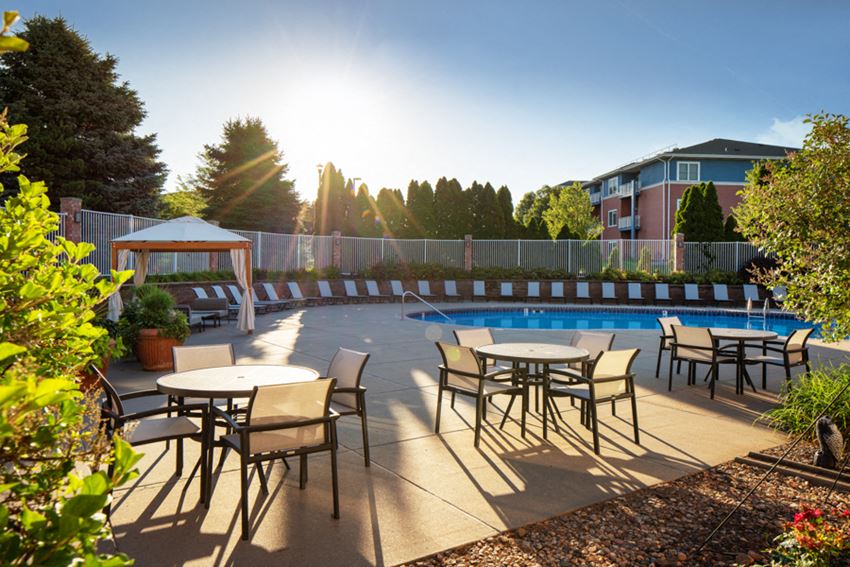 a patio with tables and chairs next to a pool