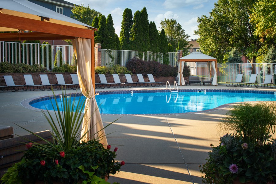 a swimming pool in a backyard with a gazebo and chairs