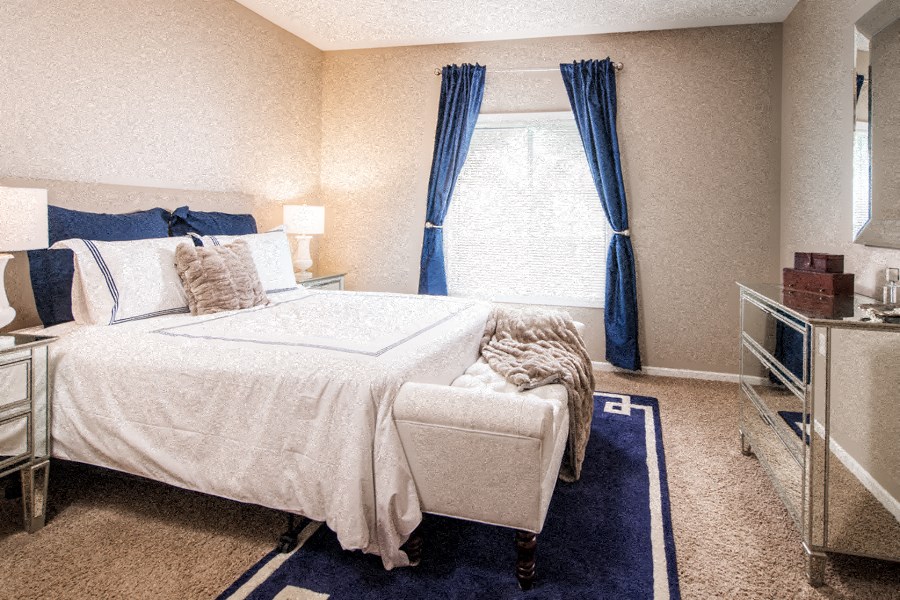 a bedroom with a bed and a window with blue curtains