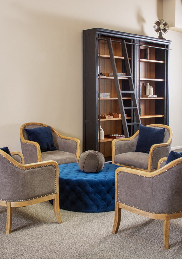 a living room with three chairs and a blue ottoman