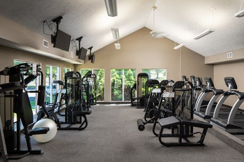 A gym with a variety of equipment including treadmills, stationary bikes, and weight machines.