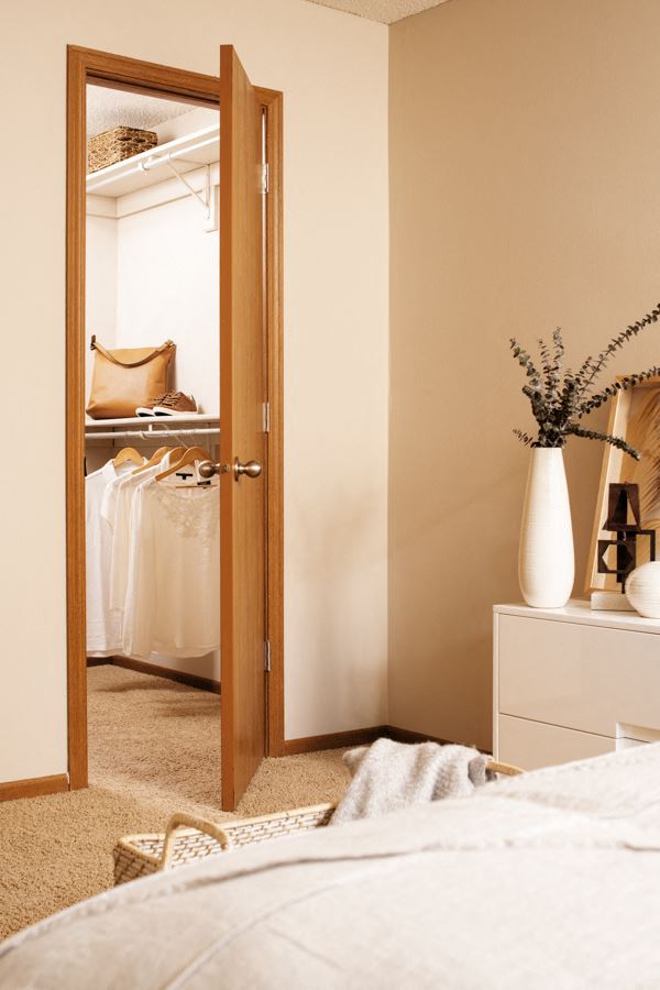 a bedroom with an open closet door and a white dresser with a vase of flowers