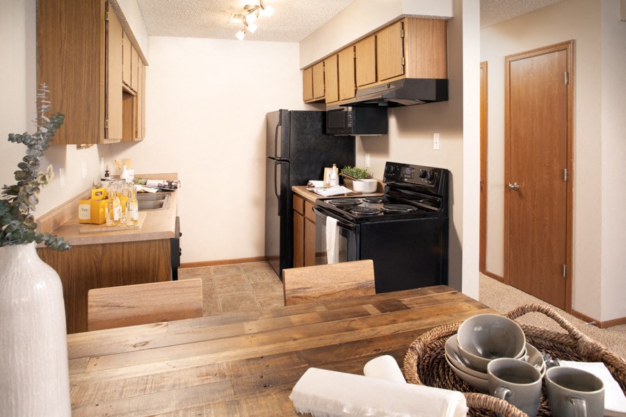 a kitchen with black appliances and a wooden table