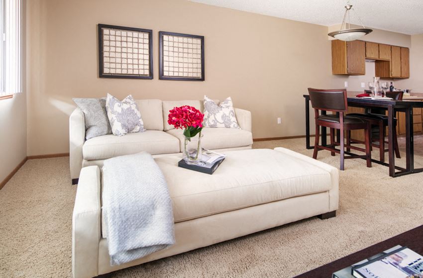 a living room with a white couch and a red flower in a vase