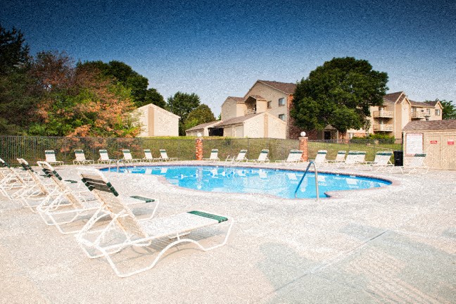 an empty swimming pool with white chairs around it