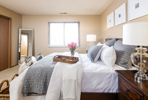 a bedroom with a large bed with white and gray pillows and a tray with