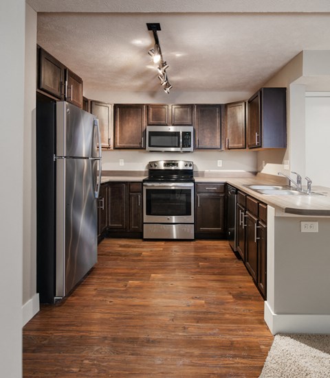 an empty kitchen with stainless steel appliances and wooden cabinets
