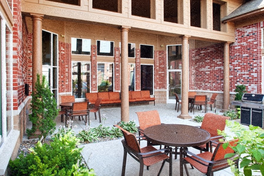 a porch with a table and chairs and a brick building