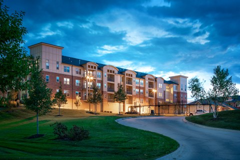 an apartment building at dusk with a winding road in front of it