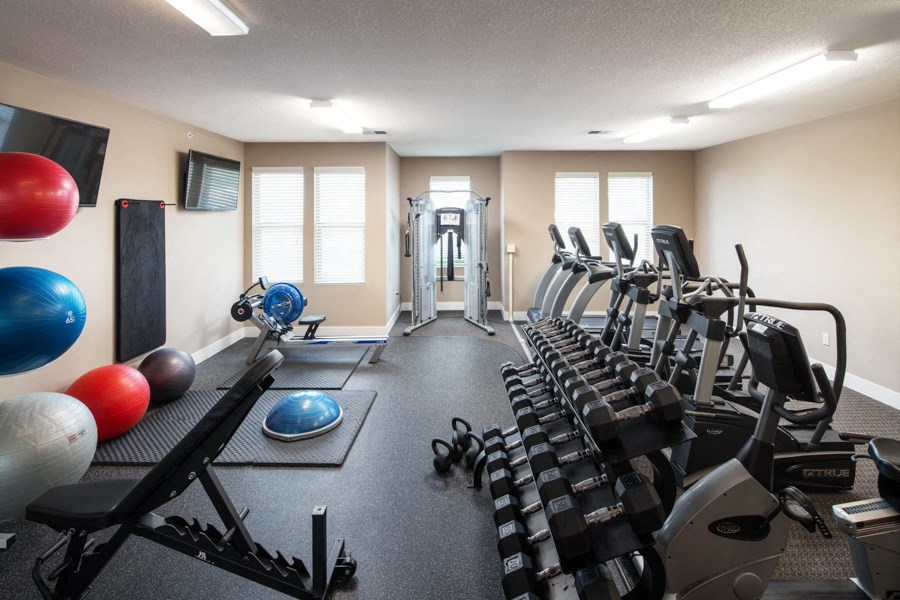 a gym with cardio equipment and weights on the floor