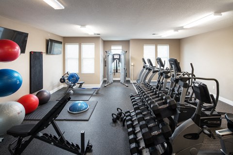 a gym with cardio equipment and weights on the floor