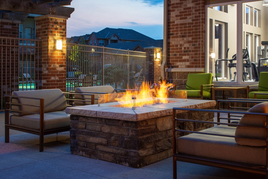 an outdoor patio with a fire pit and chairs