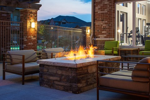 an outdoor patio with a fire pit and chairs