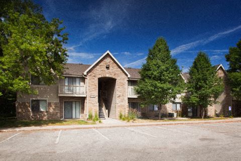 an exterior view of a brick apartment building with a parking lot in front of it