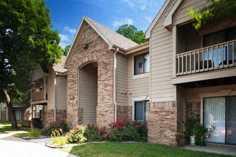 an apartment building with brick and tan walls and a sidewalk