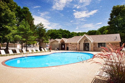 a swimming pool with chairs around it in front of a house