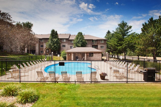a swimming pool with a fence in front of an apartment building
