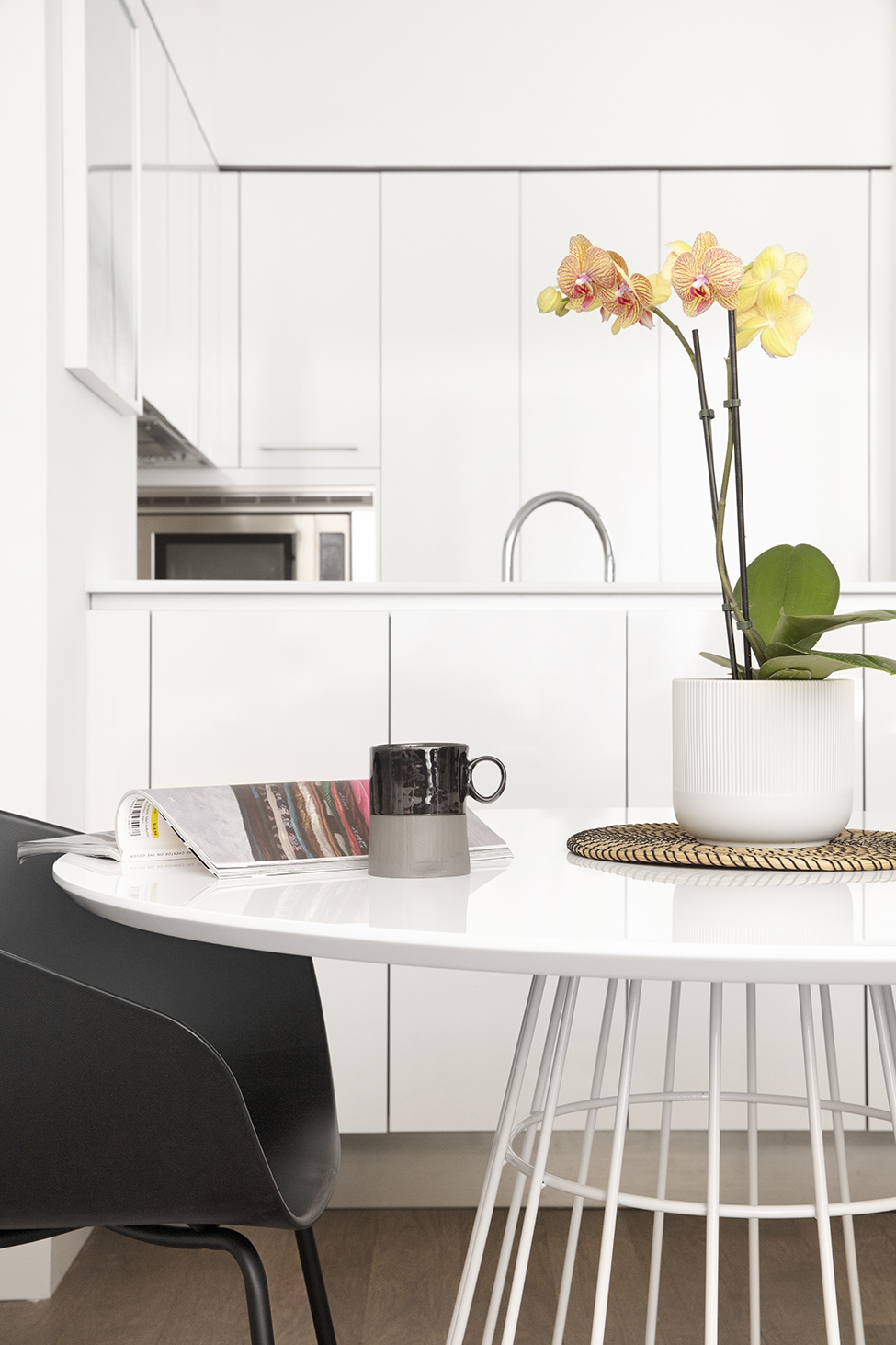 a white kitchen with a white table and a vase with flowers