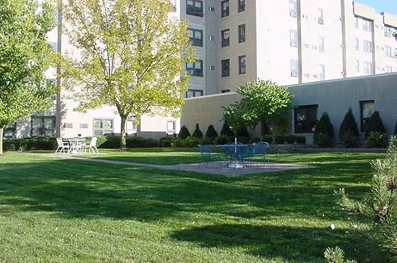 a park with a fountain in front of an apartment building