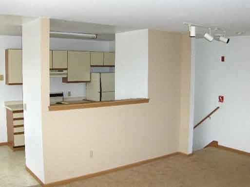 an empty living room with a kitchen in it