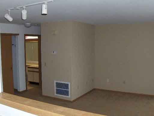 an empty living room with a heater in the wall