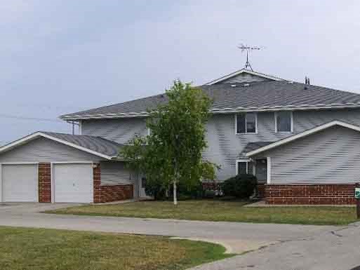 a white house with two garage doors and a tree