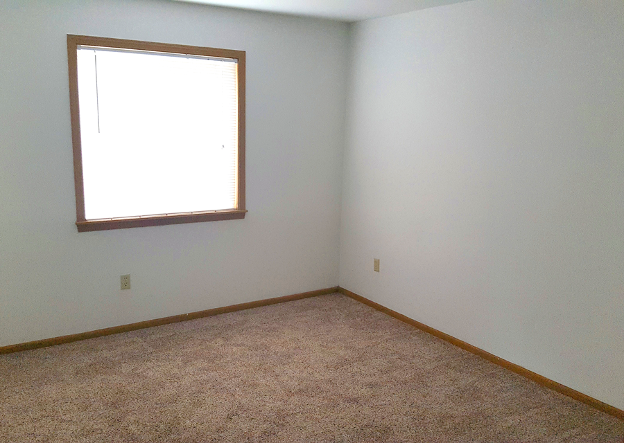 an empty room with a window and carpet