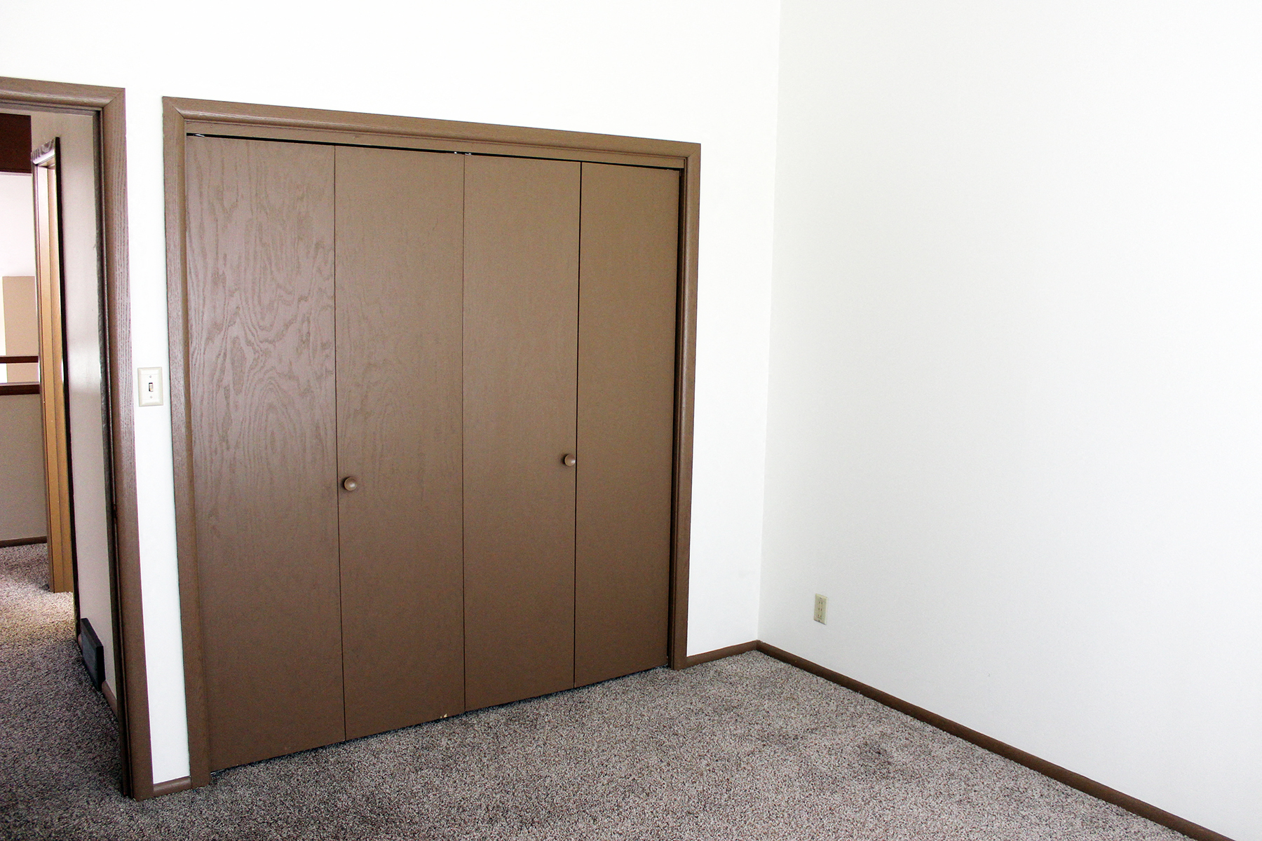 a bedroom with two closet doors and a carpeted floor