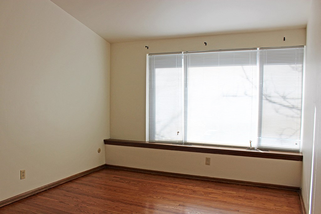 a living room with a large window and wooden floors