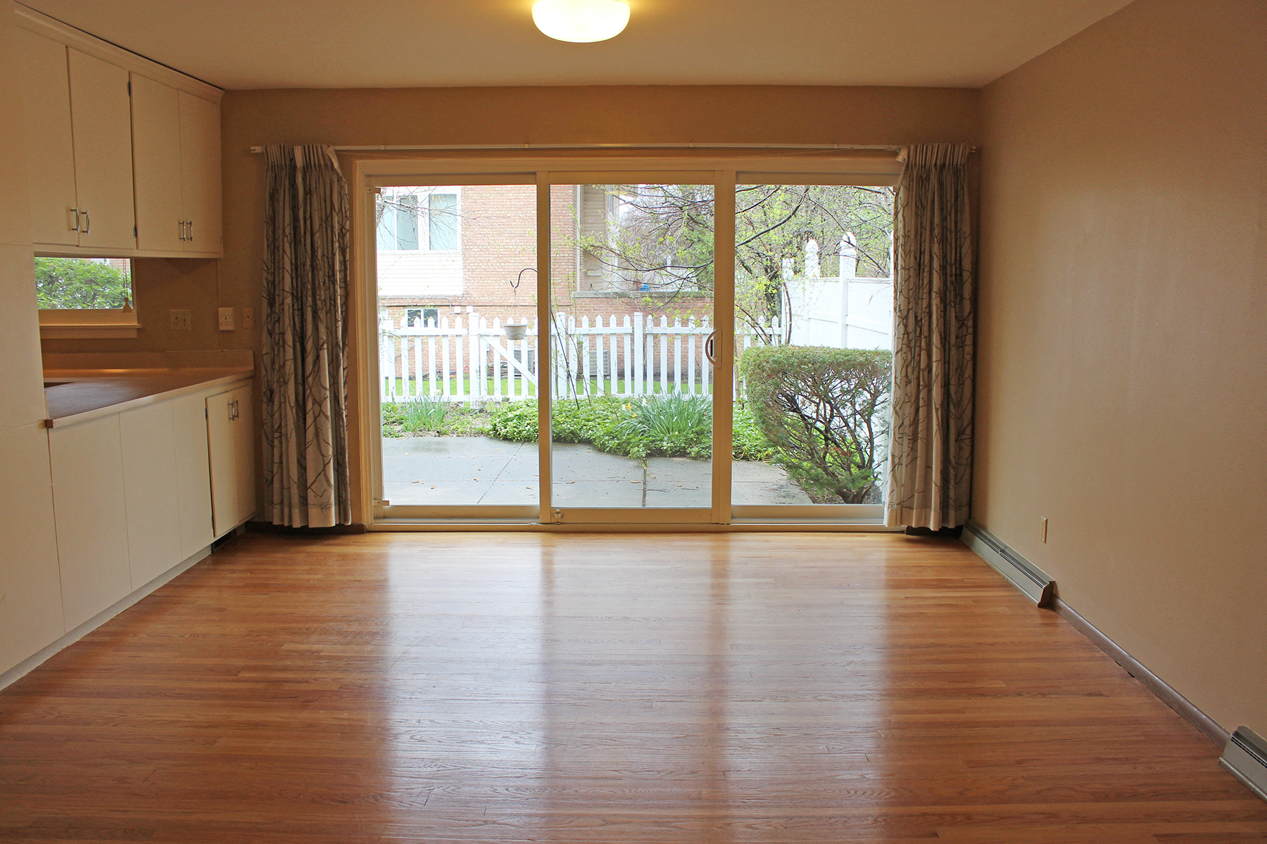 an empty living room with wood floors and a sliding glass door