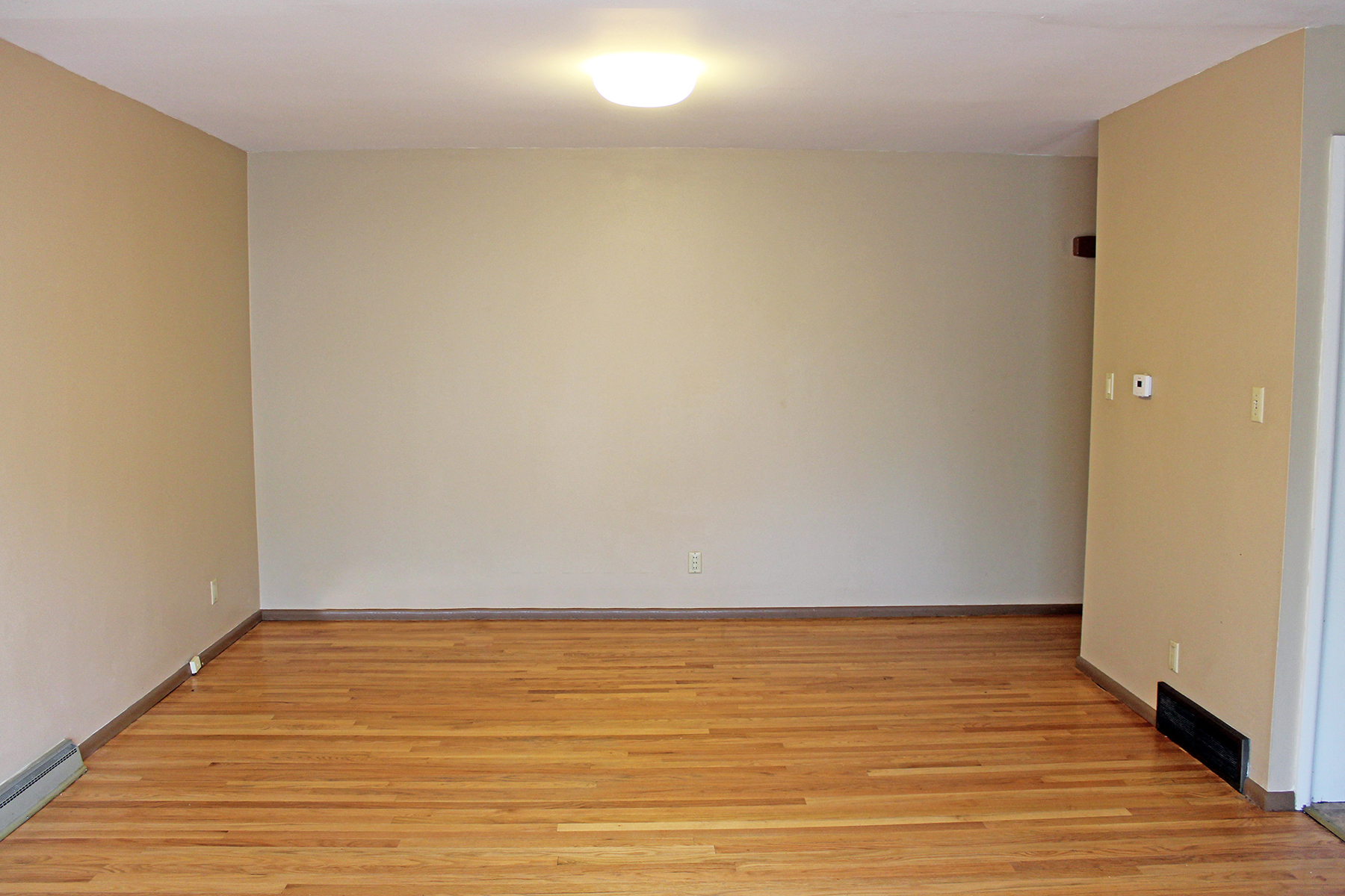 an empty room with wooden floors and a white wall