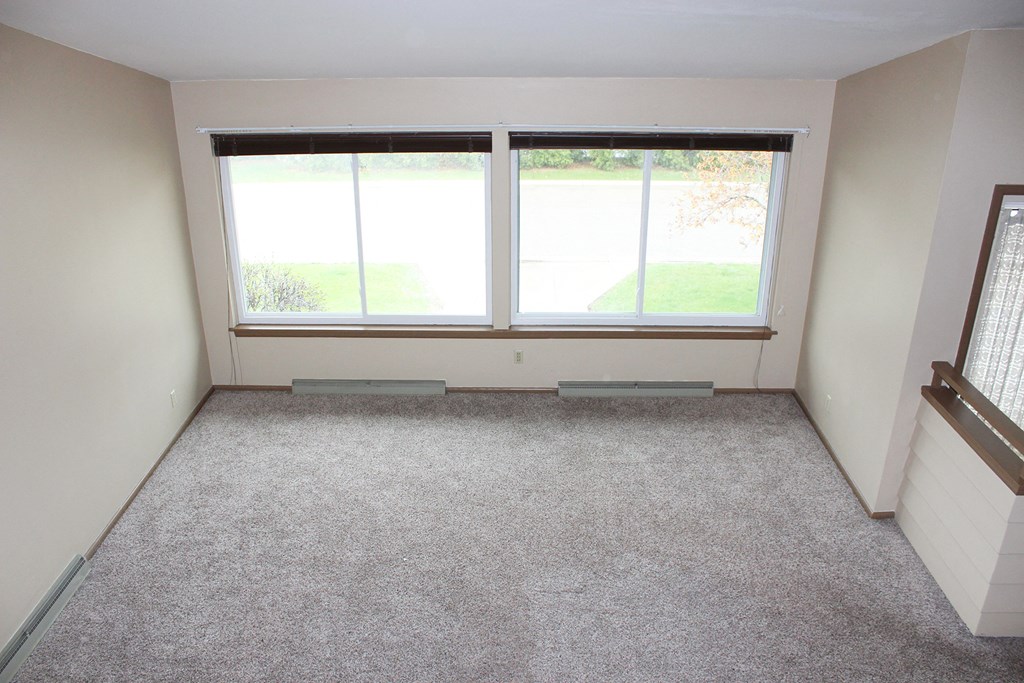 an empty room with three windows and a carpeted floor
