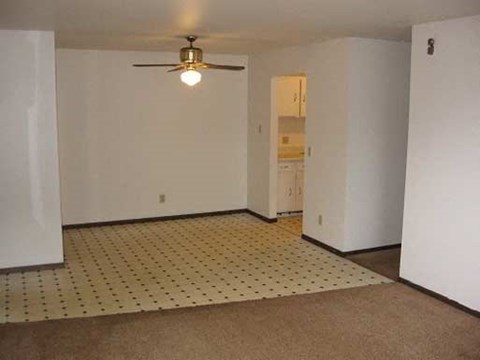 an empty living room with a ceiling fan