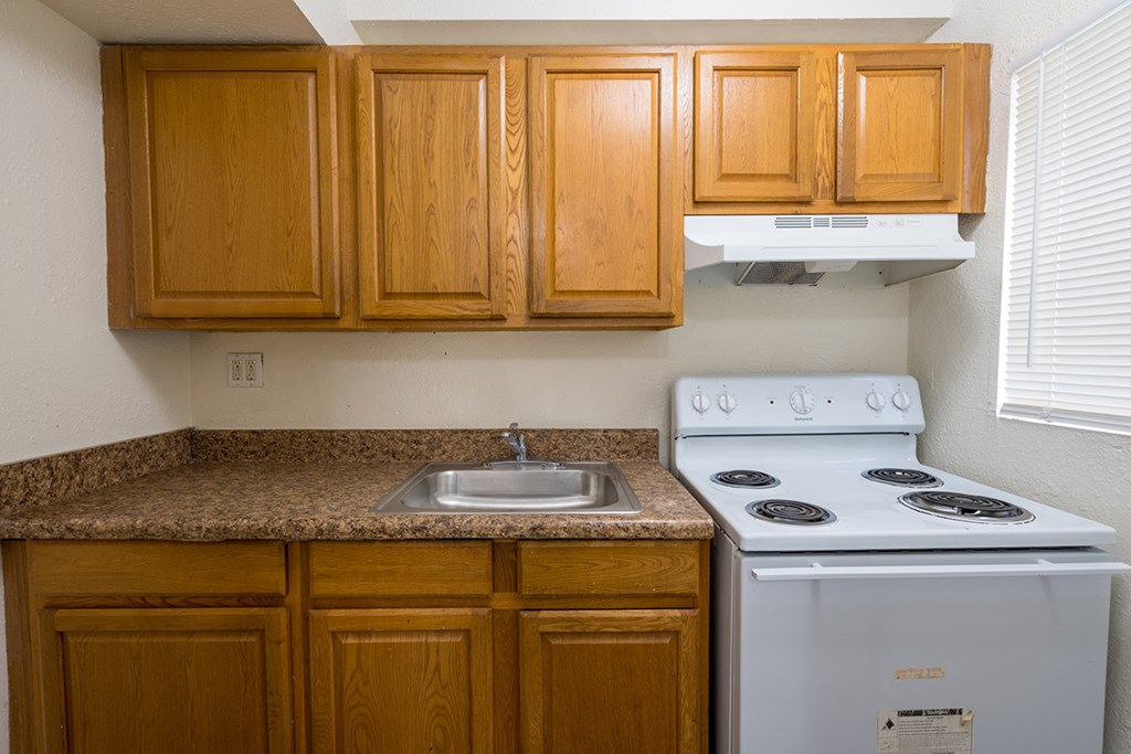 a kitchen with a stove and sink and wooden cabinets