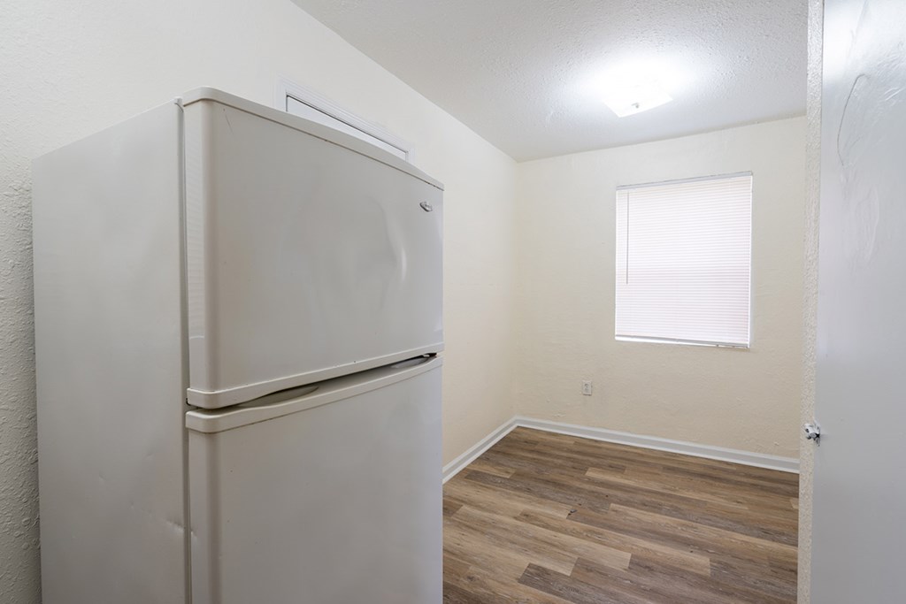 an empty room with a refrigerator and a window