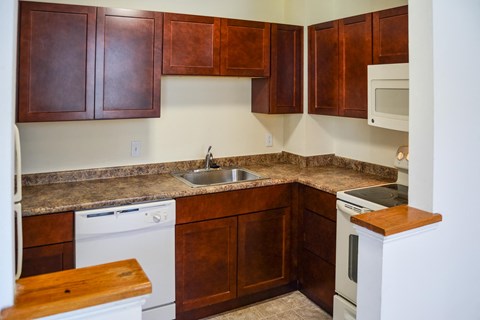 A kitchen with brown cabinets and a white dishwasher.