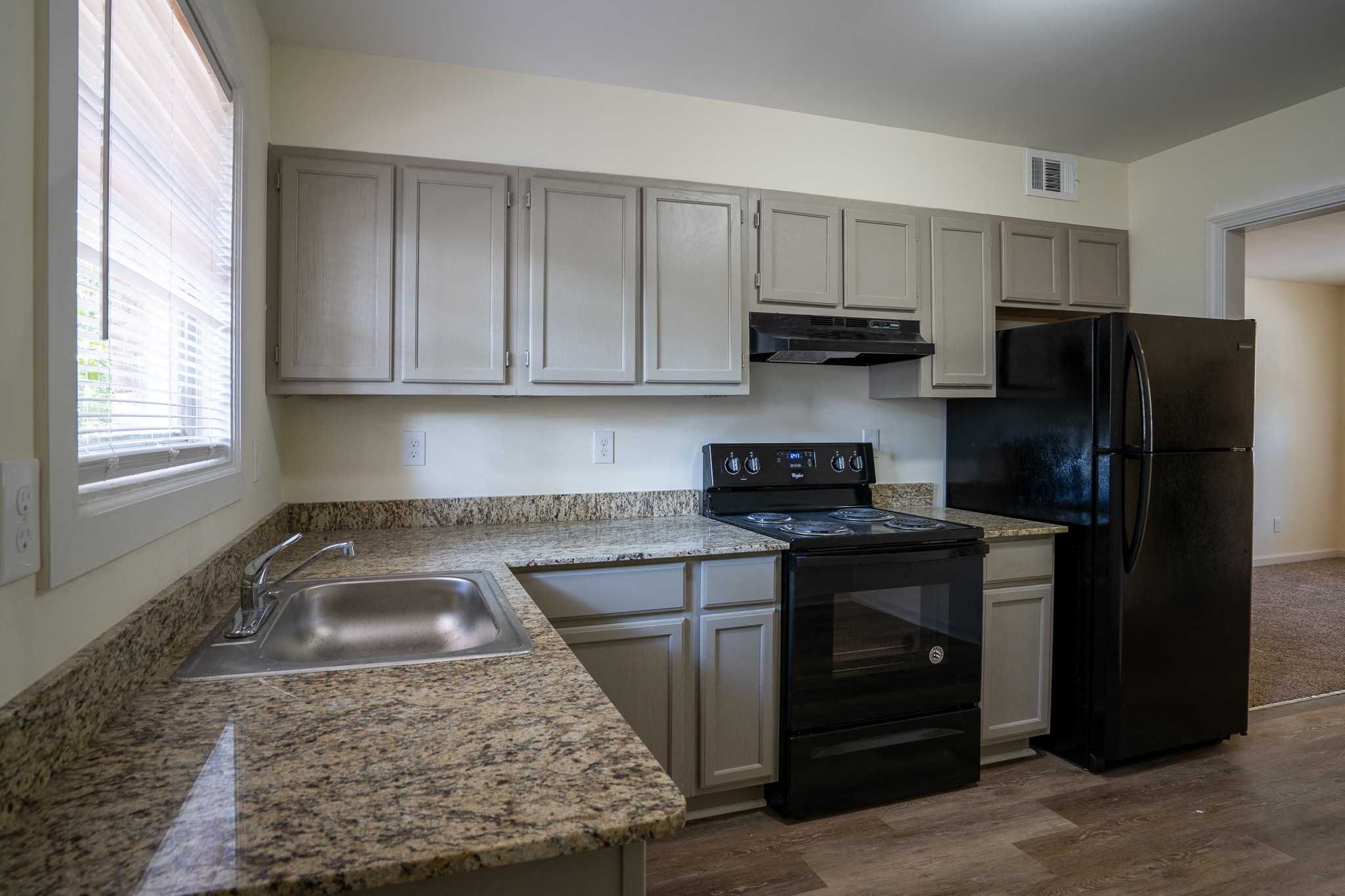 an empty kitchen with granite counter tops and black appliances