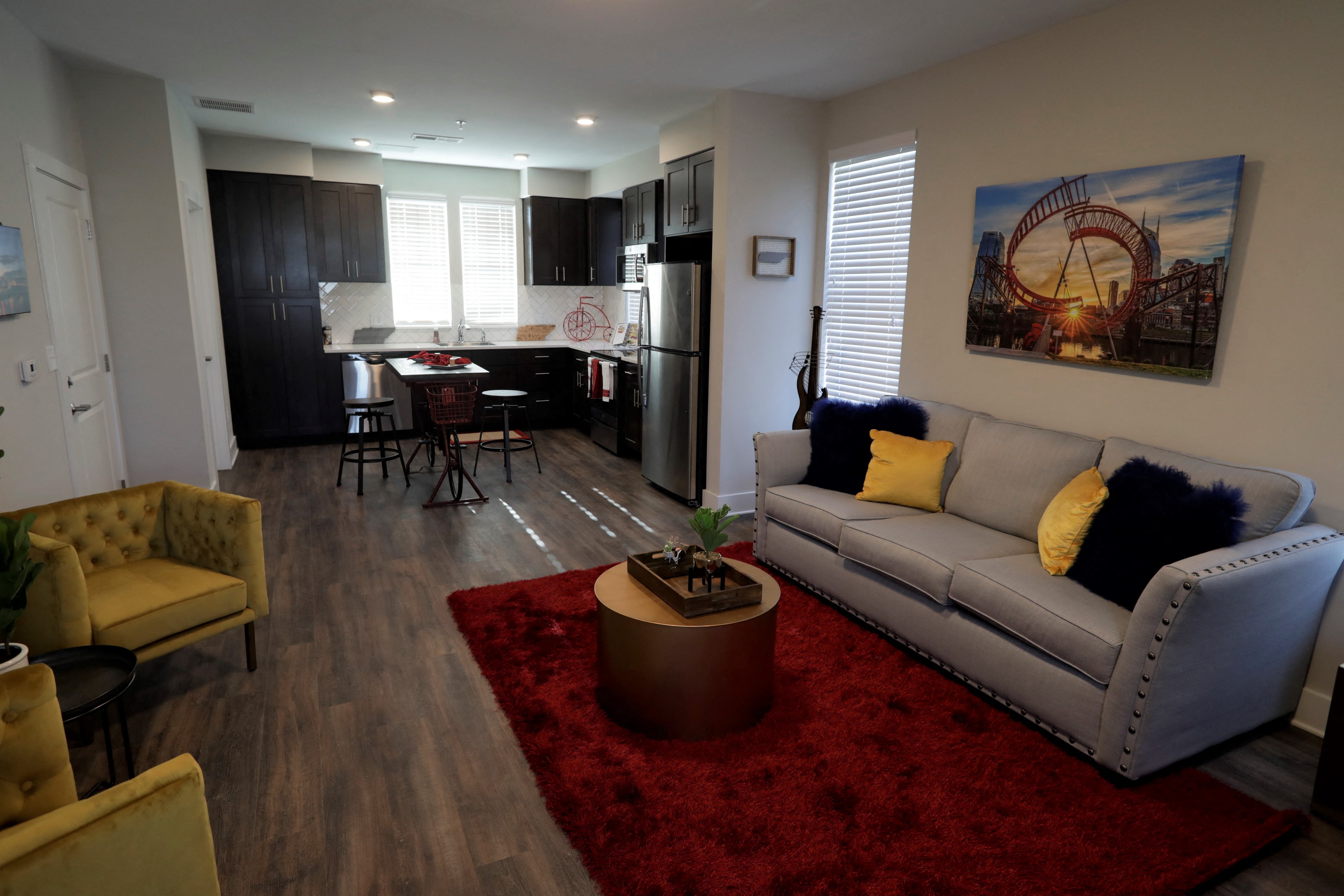 a living room and kitchen with a red rug and a couch