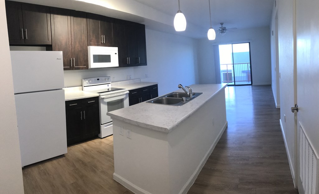 an empty kitchen with white counter tops and black cabinets
