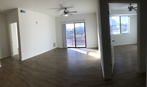 an empty living room with wooden floors and a ceiling fan