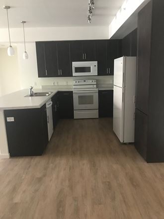 an empty kitchen with black cabinets and white appliances