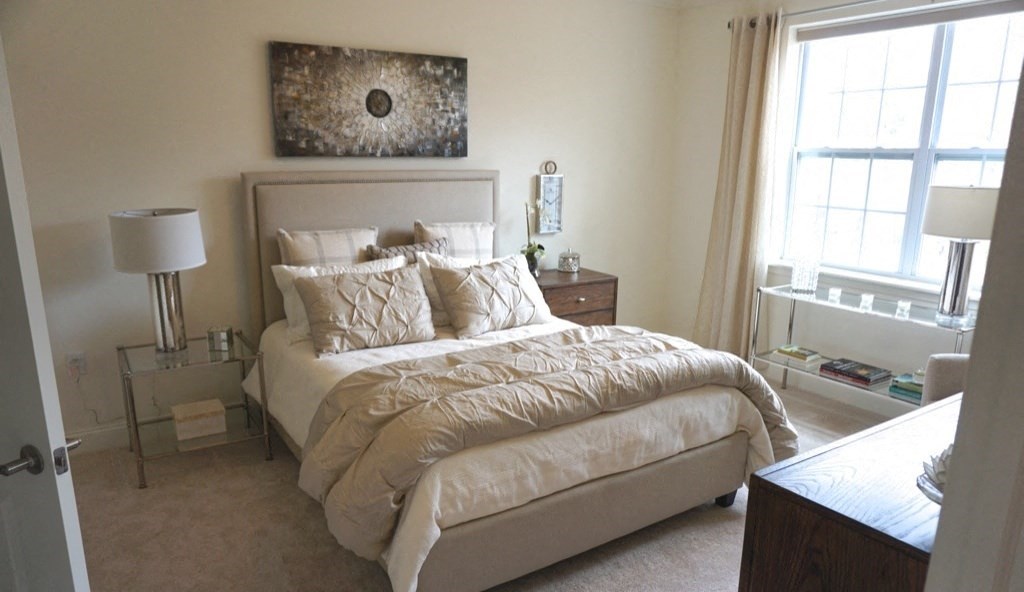 a neutral bedroom with a large bed and a window