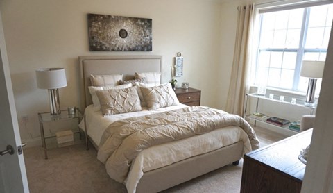 a neutral bedroom with a large bed and a window